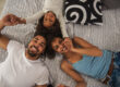 Photo illustrative de deux adultes et d’un enfant souriants, allongés et se tenant les mains.